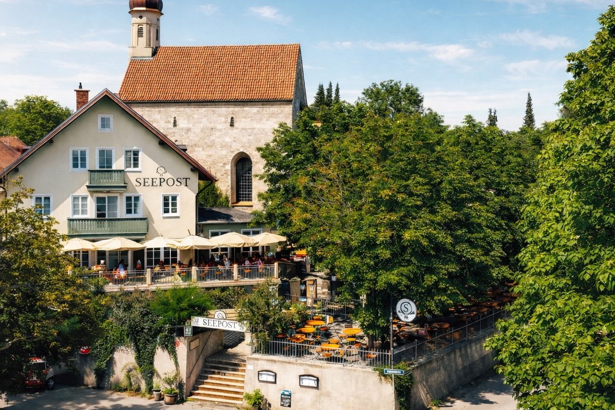 Restaurant mit Terrasse umgeben von Bäumen und einem historischen Gebäude im Hintergrund.